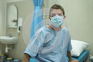 Attractive and scared man infected by covid-19 - dramatic portrait of adult male in face mask receiving treatment at hospital