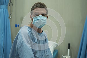 Attractive and scared man infected by covid-19 - dramatic portrait of adult male in face mask receiving treatment at hospital