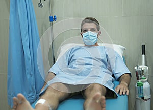 Attractive and scared man infected by covid-19 - dramatic portrait of adult male in face mask receiving treatment at hospital