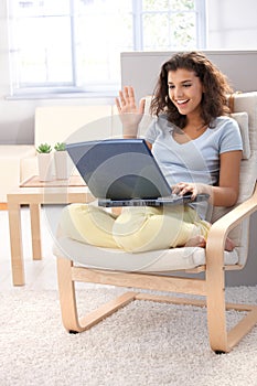 Attractive schoolgirl using laptop at home smiling