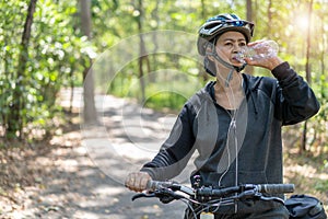 Attractive senior asian woman drinking water from bottle with bicycle