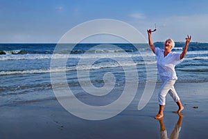 Attractive senior grey haired woman dancing near sea shore