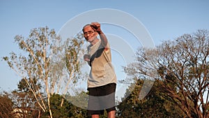 Attractive senior sportive man in boxing stance to exercises in the park for good health. Healthcare concept.