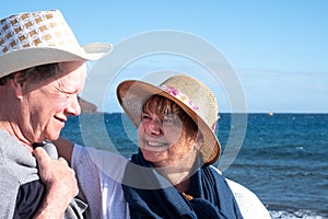 An attractive senior woman looks at his husband with love.  Windy day at the beach with a blue water and blue sky