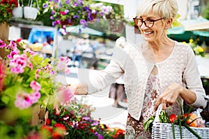 Attractive senior woman shopping in an outdoors fresh flowers market