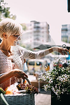 Attractive senior woman shopping in an outdoors fresh flowers market