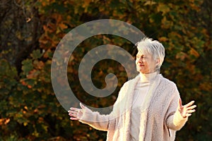 Attractive senior woman with spread arms in autumn