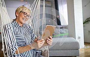 Attractive senior woman using a tablet computer relaxing at home