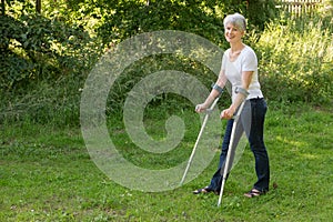 Attractive senior woman walking with crutches