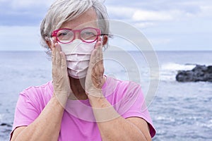 Attractive senior woman wearing medical mask due to covid-19 coronavirus enjoys nature and beach vacation in Tenerife island.