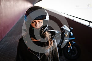 Attractive serious woman is standing next to her motobike