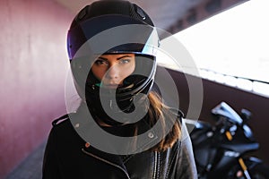 Attractive serious woman is standing next to her motobike photo