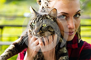 Attractive serious young woman holding her pet cat