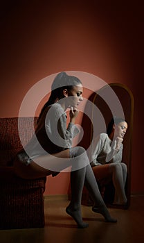 Attractive brunette in white comfortable pullover posing sitting on a sofa indoors. Portrait of sensual young woman posing