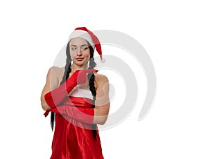 Attractive sexy dark-haired woman in a carnival costume of Santa Claus smiling cute, looking mysteriously aside and pointing with