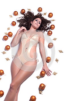 Attractive woman with shine gold bikini lying, Christmas balls around her