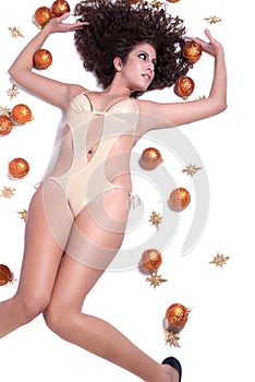 Attractive woman with shine gold bikini lying, Christmas balls around her