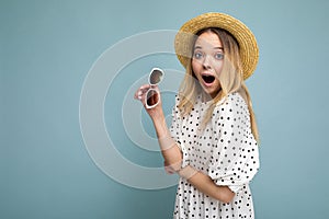 Attractive shocked young blonde woman wearing everyday stylish clothes and modern sunglasses isolated on colorful