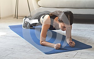 Attractive slim girl in sportswear is doing abs exercises on the floor