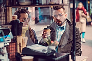 Attractive smart couple is enjoying coffee while sitting outside at small coffeesho