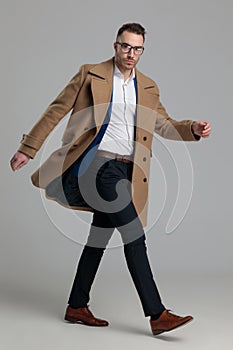 Attractive smartcasual guy wearing long coat walking