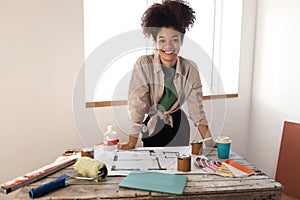 Attractive smiling African woman holds tablet and coffee and checks house plan