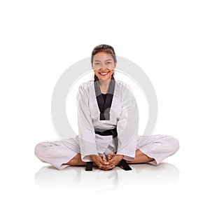Attractive smiling Asian karateka girl sitting in lotus position