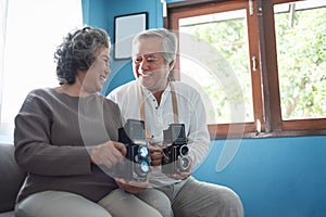 Attractive Smiling Asian Senior couple holding vintage camera at home