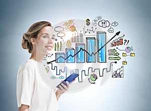 Attractive smiling businesswoman in formal wear holding a phone and standing near light blue wall with creative colorful bar chart