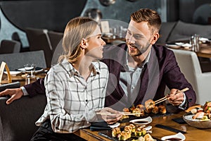 Attractive smiling couple amorously looking at each other while having dinner