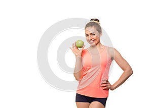 Attractive smiling fit caucasian woman in pink sports top holds a green apple in hand, isolated on white. Girl promotes