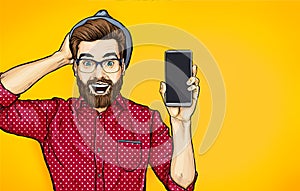 Attractive smiling hipster in specs with phone in the hand in comic style. Pop art man in hat holding smartphone. photo