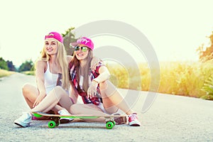 Attractive smiling hipster teenage friends with skateboard