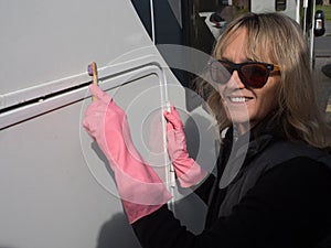 Atractivo dama mano con limpia su casa rodante recreativo vehículo cepillo de dientes. rosa goma guantes gafas de sol 