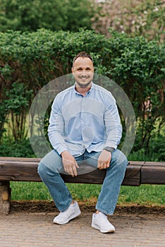 Attractive smiling man sitting alone on a park bench