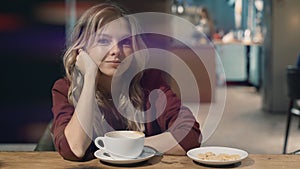 Attractive smiling woman in cafe dreaming and waiting for a meeting. looking directly to camera. Lense flare