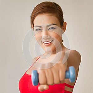 Attractive, smiling woman model with dumbbell punching