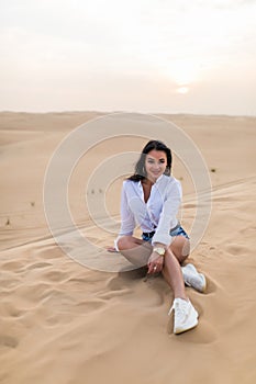 Attractive smiling woman posing in desert sand on sunset, travel safari on vacation, sunny summer day