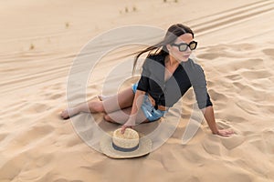 Attractive smiling woman posing in desert sand on sunset, travel safari on vacation, sunny summer day