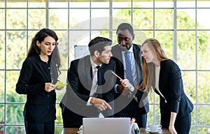 Attractive smiling young adult caucasian businessman leader discussing with the multiracial colleagues. CEO looking and pointing