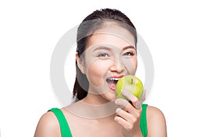 Attractive smiling young asian woman eating green apple isolated