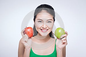 Attractive smiling young asian woman holding green apple isolated over white background