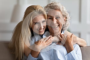 Attractive smiling young blonde woman embracing older pleasant mommy.