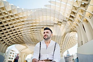 Attractive smiling young man influencer.Tourist visiting Setas de Seville,Metropol Parasol, site seeing attractions.Vacation in