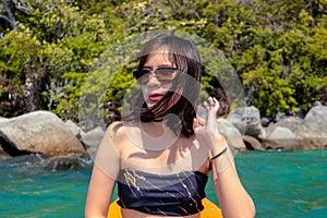 Attractive smiling young woman model in bikini sunglasses and straw hat smiles happily at camera