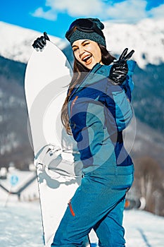 Attractive snowboard girl smiling and posing on mountain and slope background.