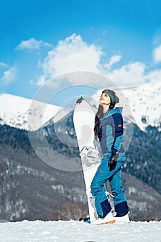 Attractive snowboard girl smiling and posing on mountain and slope background.