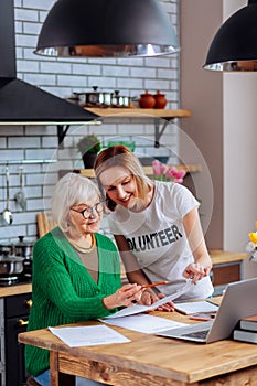 Attractive social worker assisting granny in figuring out with papers