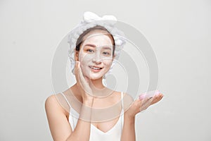 Attractive spa woman applying facial clay mask  on white background