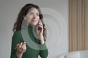 Attractive Spanish young businesswoman enjoying telephone conversation, using smartphone at work